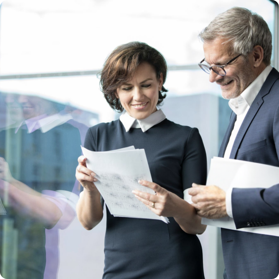 Two colleagues collaborating on a project, looking at paper reports.
