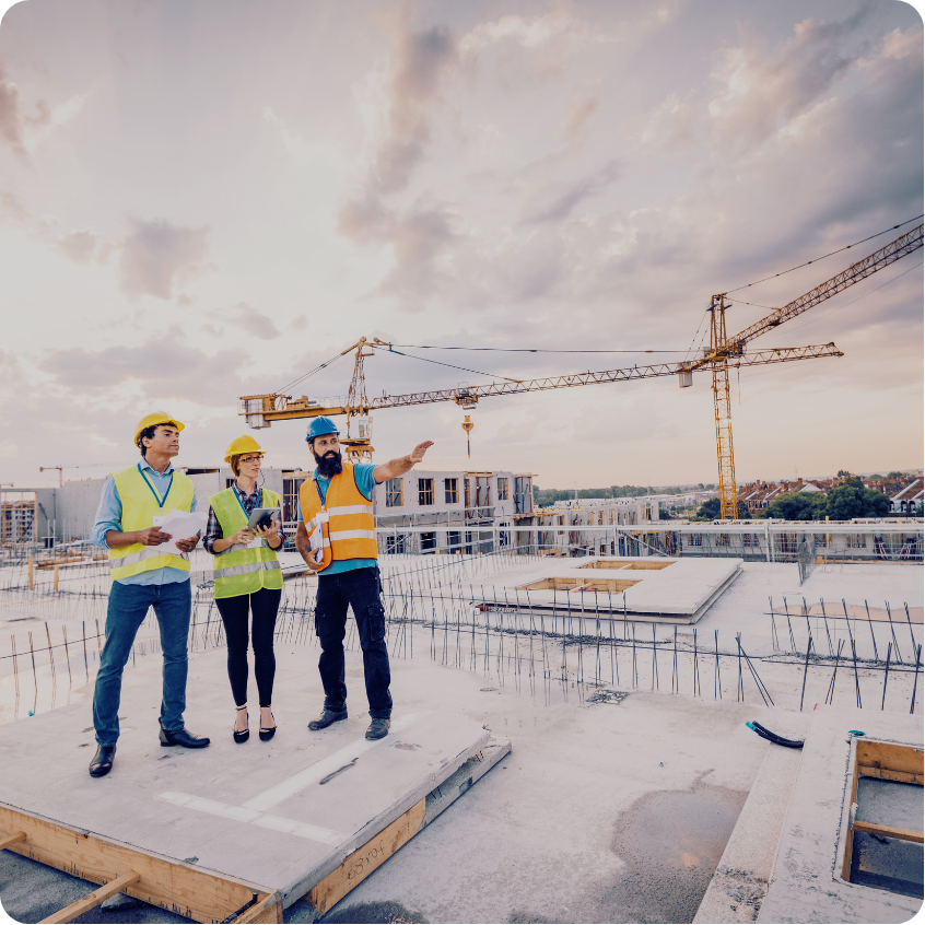 Construction team in safety gear reviewing plans and pointing out progress at an active building site.