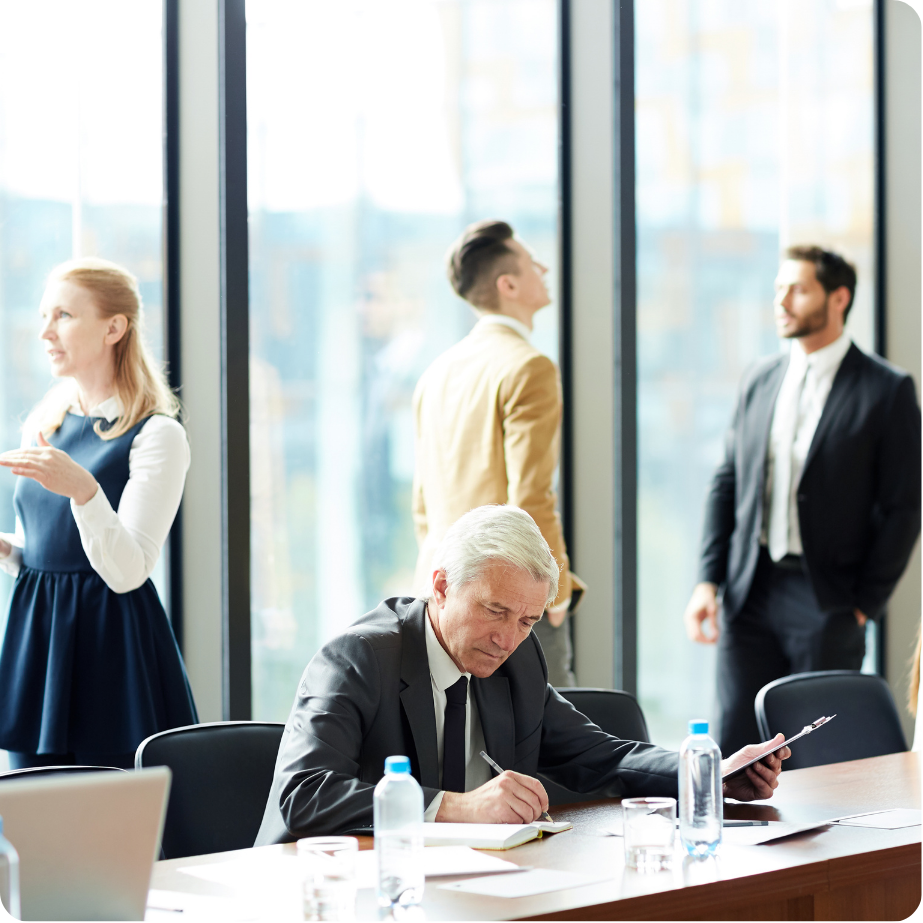 Professional reviewing project performance surrounded by other professionals in an office setting.